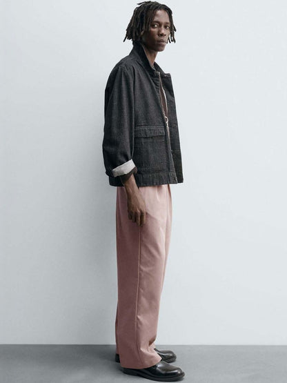Men Pleated Trousers in relaxed fit pink color, styled with a black jacket, perfect for a trendy look.